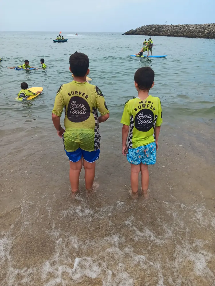 Duas crianças a entrar no mar com as licras do camp