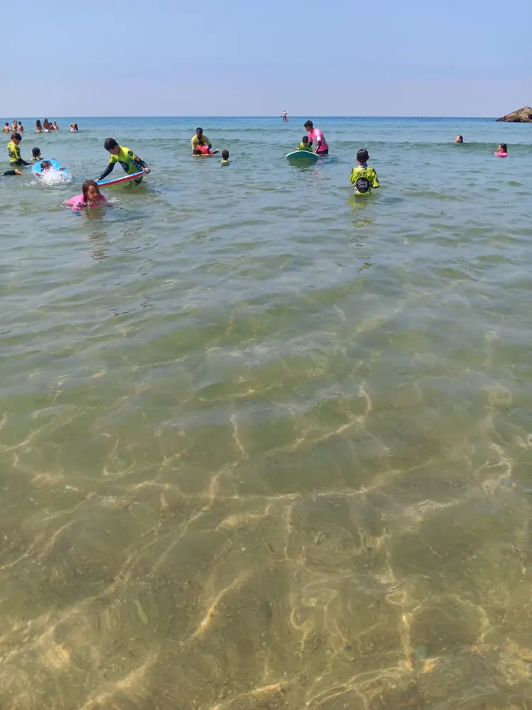 Crianças na água, durante a aula de surf